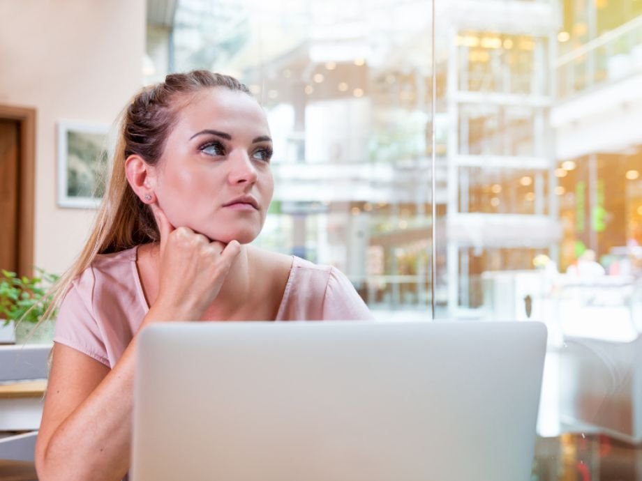 Ondernemer kijkt peinzend naar laptop, twijfelend door vergelijking met anderen.